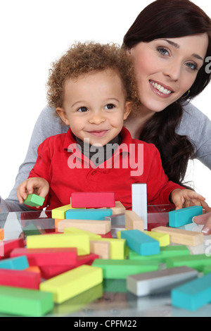 La madre si sedette con figlio riproduzione di blocchi di costruzione Foto Stock