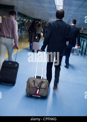 Imprenditori sfocata trascinando le loro borse trolley su un aeroporto Foto Stock
