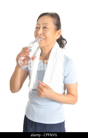 Donna senior di bere acqua da bottiglie in pet Foto Stock