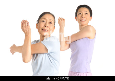 Senior donna e metà donna adulta stretching bracci superiori Foto Stock