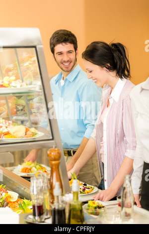 Caffetteria pranzo ufficio giovani colleghi scegliere insalata self-service Foto Stock