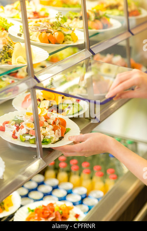 Buffet di insalata fresca self-service display cibo mano umana prendere la piastra Foto Stock