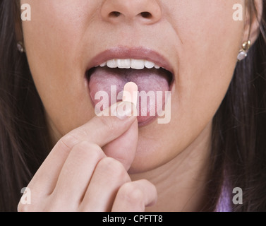Extreme close-up immagine di una giovane donna di prendere una pillola. Foto Stock