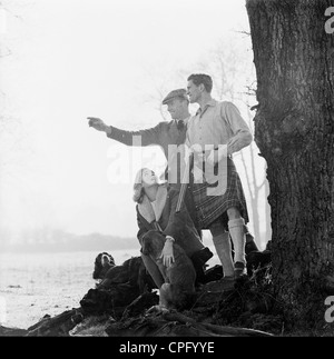 Un annuncio da anni sessanta la promozione di Scottish realizzate sigarette; un uomo in kilt con una giovane donna e cani sulla sponda di un lago. Foto Stock