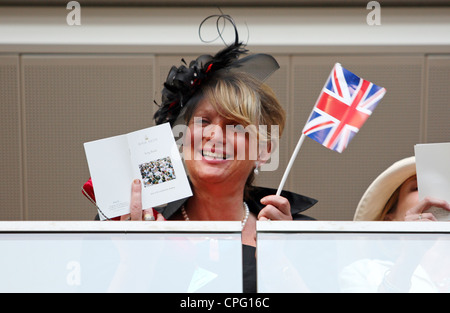 Donna con una piccola bandiera del Regno Unito e una Royal Ascot song book a corse di cavalli, Ascot, Regno Unito Foto Stock