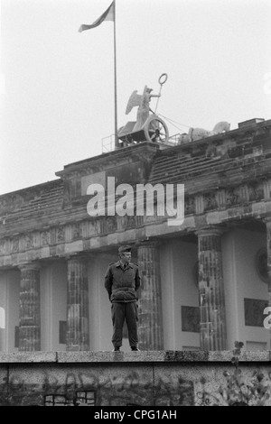 Una guardia di confine durante l'apertura del muro di Berlino alla Porta di Brandeburgo, Berlino, Germania Foto Stock