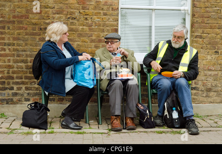 Tre persone sedute su una panchina a mangiare cibo al Batchworth Lock Canal Centro durante Rickmansworth canal festival Foto Stock