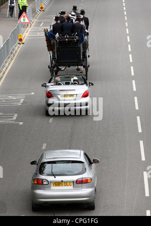 Auto guidando lentamente dietro una carrozza trainata da cavalli, Ascot, Regno Unito Foto Stock