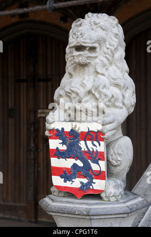 Pietra scolpita la statua di un leone azienda uno scudo con lo stemma del Fiandre - strisce rosse e bianche con un blue lion. Foto Stock