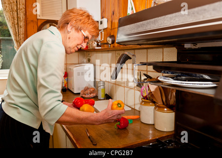 Donna anziana la preparazione di cibi a casa nella sua cucina Foto Stock