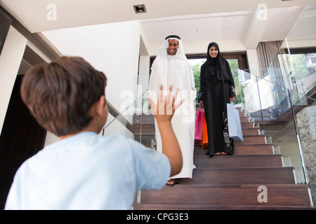 Ragazzo a salutare i suoi genitori, arrivando a casa dal carrello. Foto Stock