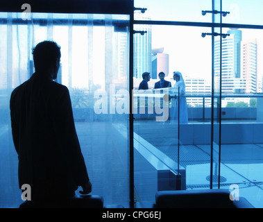 Un uomo d'affari alla ricerca sui suoi colleghi collega la porta di vetro. Foto Stock