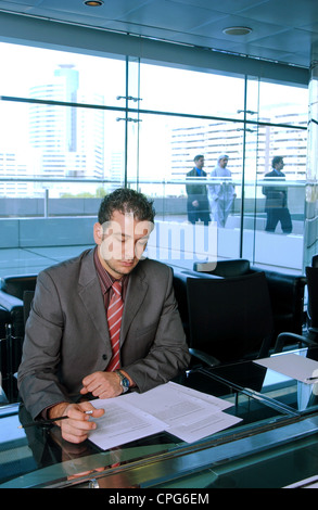 Un imprenditore concentrandosi sul suo lavoro mentre il suo compagno collega visto dallo sfondo. Foto Stock