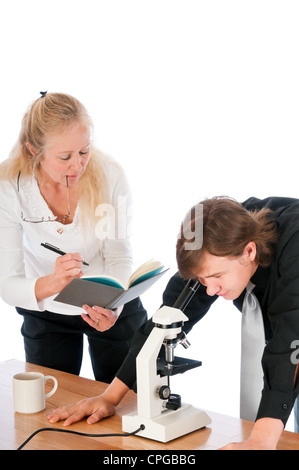 Femmina professore insegnamento un maschio di studenti in una classe di biologia, utilizzando un microscopio. Isolato su uno sfondo bianco. Foto Stock