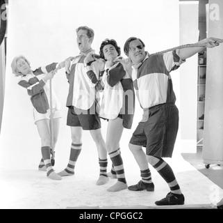 Pubblicità ancora dagli anni Sessanta. Un gruppo di attori vestiti di capi di abbigliamento sportivi in uno studio fotografico a giocare con una fune. Foto Stock