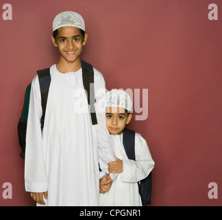 Fratelli che trasportano borse tracolla, ritratto, sorridente Foto Stock