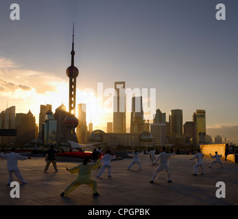 Tai chi esercizio di gruppo rivolto verso il sorgere del sole e il Pudong alte torri dal Bund Shanghai in Cina Foto Stock