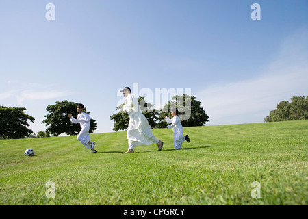 Padre con figli a giocare a calcio in posizione di parcheggio Foto Stock