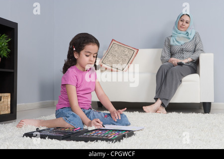 Madre araba con la figlia a fare i compiti in salotto Foto Stock