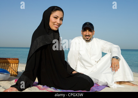 Coppia giovane seduto sulla spiaggia, sorridente, ritratto Foto Stock
