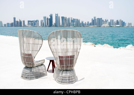 Moderni posti a sedere esterni a waterfront cafe con vista sullo skyline di Doha in Qatar Foto Stock