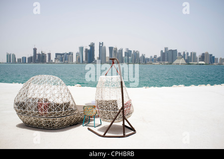 Moderni posti a sedere esterni a waterfront cafe con vista sullo skyline di Doha in qater Foto Stock