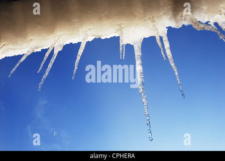 Ghiaccioli e neve contro il cielo blu in primavera Foto Stock