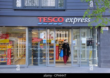 Donna asiatica lascia Tesco Express con il suo shopping a Glasgow. Foto Stock