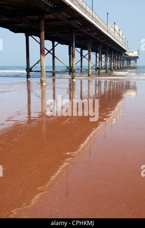 Pier riflessa nella sabbia rossa che è tipico del South Devon Coast, Paignton Inghilterra. Foto Stock