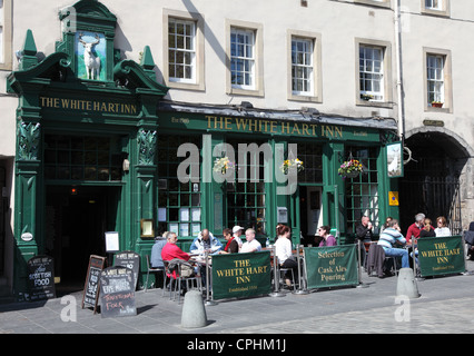 Le persone sedute a bere al di fuori del White Hart Inn entro il Grassmarket, Edimburgo Scozia UK Foto Stock