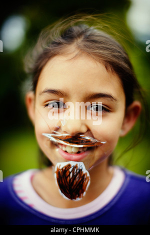 Movember. Ragazza con il suo in casa di baffi e barba che ha bloccato per il suo volto con il nastro adesivo. Foto Stock