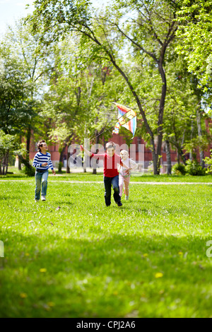 Immagine di gioiosa amici giocando con il kite in esterno Foto Stock