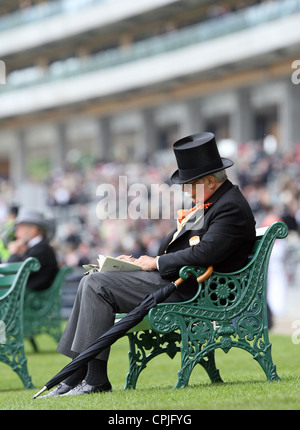 Elegantemente vestito uomo seduto su una panchina, Ascot, Regno Unito Foto Stock