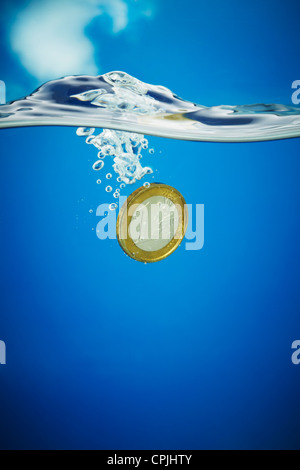 1 Euro moneta che affonda in acqua blu Foto Stock