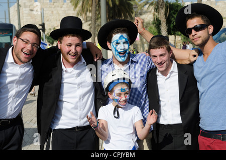 Giovane con una bandiera Israeliana dipinto sul suo volto la messa in pausa con la gente. Gerusalemme. Israele. Foto Stock