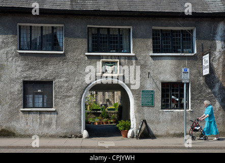 Old Lady a camminare lungo la facciata di Sandnes ospedale, con datestone di 1659, Highgate, Kendal Cumbria, England Regno Unito Foto Stock