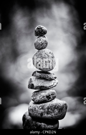 Impilati pietre equilibrata sul bordo di un fiume nella campagna inglese. Monocromatico Foto Stock