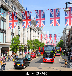 Black Cab & autobus in Oxford Street al di fuori di Selfridges con Giubileo Unione martinetti che possono anche essere nel luogo durante il 2012 Olimpiadi Foto Stock