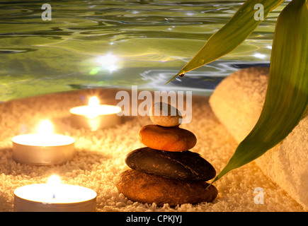 Spa pietre con candele e acqua sul tovagliolo Foto Stock