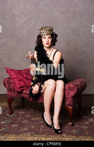 Una bruna donna pone come 1920's enca godendo di un martini Foto Stock