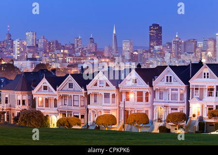 Skyline di San Francisco dietro le case in stile vittoriano di notte - California USA Foto Stock