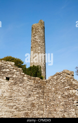 Tra le rovine storiche del guardare la torre rotonda a Monasterboice, inizio insediamento monastico in Irlanda. Foto Stock