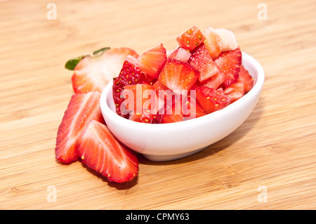 Cumulo di fragole tagliate su un sfondo di legno Foto Stock