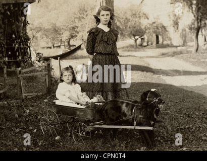 La sorella maggiore con la sorella più giovane di cane Giocattolo disegnato carro Foto Stock