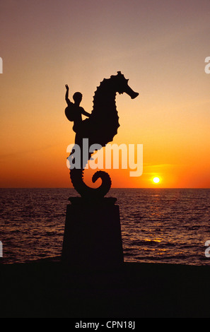 Un tramonto sagome una statua di bronzo di un cavalluccio marino e il suo giovane pilota, il simbolo iconico del beach resort città di Puerto Vallarta in Messico. Foto Stock