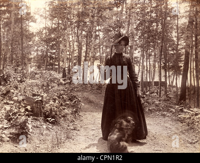 Donna vittoriana prendendo cane per una passeggiata nel bosco