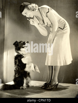 Insegnamento di bellezza il suo cane di sedersi fino Foto Stock