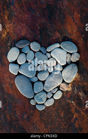 Forma di cuore i ciottoli su una texture di sfondo di ardesia Foto Stock