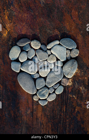 Forma di cuore i ciottoli su una texture di sfondo di ardesia Foto Stock