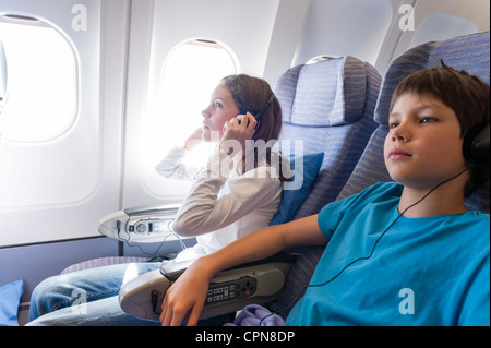 I bambini guardare film su aereo con le cuffie Foto Stock